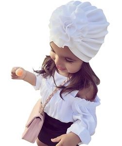 Détail d'un turban blanc en coton pour bébé avec une grande fleur 3D décorative pour enfant