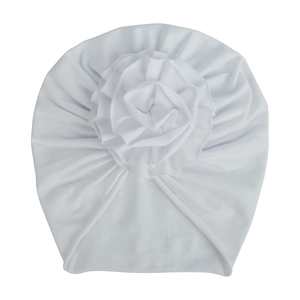 Détail d'un bonnet turban blanc en coton pour bébé orné d'une grande fleur plissée multicouche