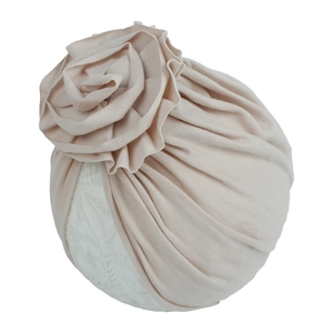 Détail d'un bonnet turban pour bébé avec grande fleur plissée en tricot rose pâle