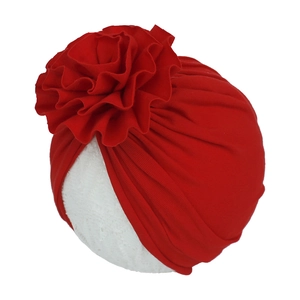 Gros plan du turban pour bébé en coton rouge plissé avec une grande fleur multicouche