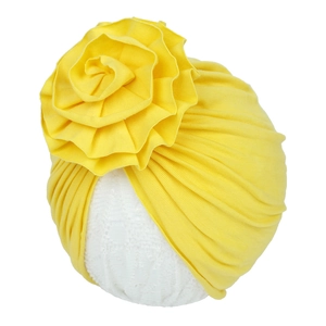 Détail d'un turban pour bébé en coton jaune avec une grande fleur plissée décorative