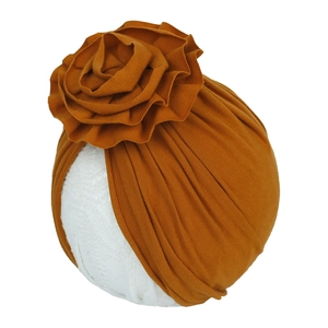 Détail d'un turban pour bébé en tricot jaune gingembre avec une grande fleur 3D faite main
