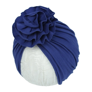 Détail du bonnet tricoté bleu marine pour bébé avec grande fleur plissée à volants