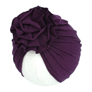 Détail du bonnet en maille violet foncé orné d'une grande fleur plissée en relief 3D