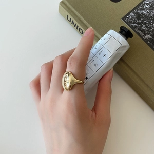 Macro shot of minimalist gold irregular ring on finger with glossy polished finish