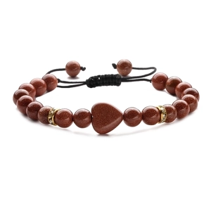Detail of red sandstone heart pendant and beads on black braided adjustable bracelet