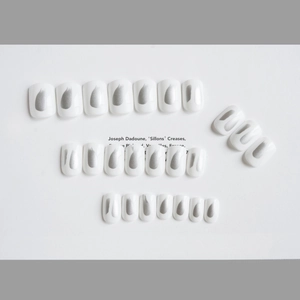 Artistic white press-on nails with silver metallic brushstrokes in a minimalist style
