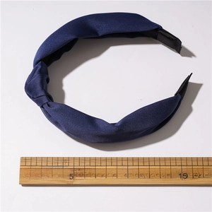 Detail shot of a navy blue satin knotted headband showing 13-14cm width measurement