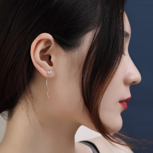 Detail of silver S925 heart stud with long wavy tassel earrings on a model