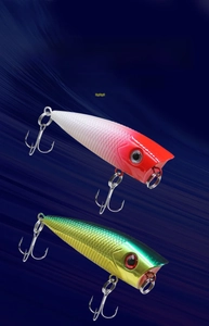 Close-up of dual color popper lures featuring lifelike fish scales and 3D eyes