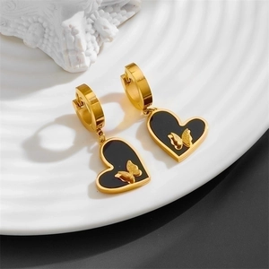 Detail of gold hoop earrings with black heart charms and gold butterfly inlay