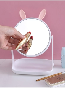 Close-up of swivel makeup mirror with cute rabbit ears and a lipstick reflection