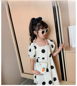 Dettaglio di un vestito a pois per bambina con borsa in paglia e decoro coniglietto