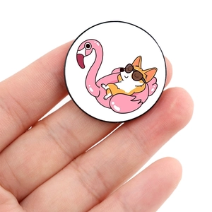 Close-up of a round Corgi badge on a pink flamingo float held by fingers