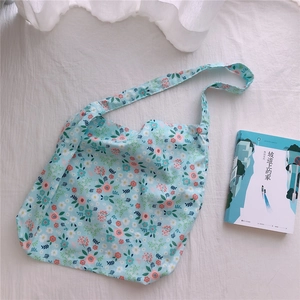 Detail of light blue floral cotton tote bag with daisy pattern and soft fabric texture