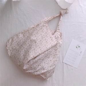 Detail of floral cotton tote bag featuring elegant knotted handles and soft fabric texture