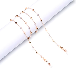 Golden eyewear chain with white pearls and metal beads on a white display stand