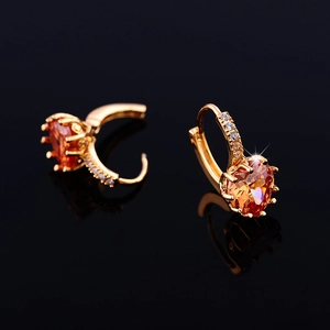 Detailed macro of 18K gold hoop earrings featuring orange heart-shaped AAA cubic zirconia