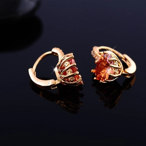 Detailed macro view of gold-plated hoop earrings with pear-cut orange gems and pavé zircons