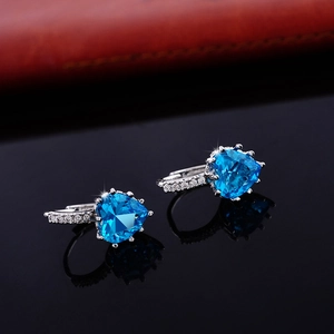 Macro shot of heart-shaped blue zircon earrings with sparkling silver diamond pavé setting