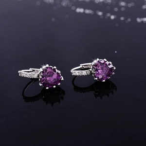 Macro shot of purple heart-shaped zircon earrings with silver clasp on black background