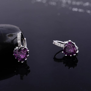 Detail of purple heart-shaped zirconia earrings with silver prong setting and micro-pave