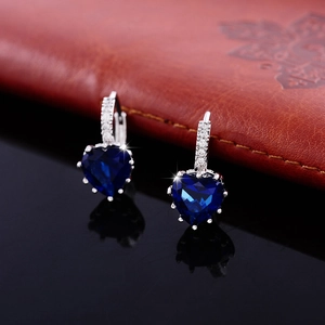 Macro detail of heart-shaped blue zircon earrings with pavé-set silver hooks