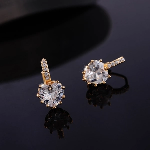 Detailed macro view of heart-shaped white zircon earrings on a reflective black base