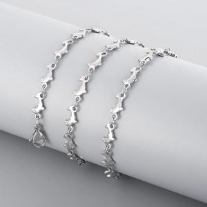Detail of silver dolphin link necklace wrapped around a grey cylinder pedestal