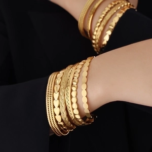 Stack of gold titanium steel bracelets featuring heart and geometric line designs on wrist