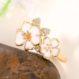 Elegant gold metal ring featuring white enamel camellia flowers with tiny clear zircons