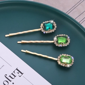 Three vintage green crystal hair clips with gold wavy metal and sparkling rhinestones