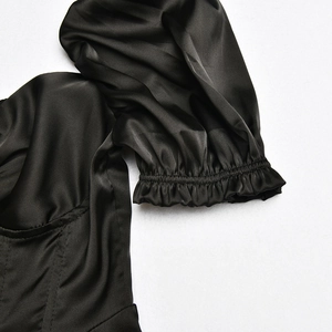 Detail of black satin dress featuring pleated puff sleeve cuffs and smooth silk texture