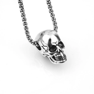 Detailed close-up of a vintage silver skull pendant with heavy box chain on white backdrop
