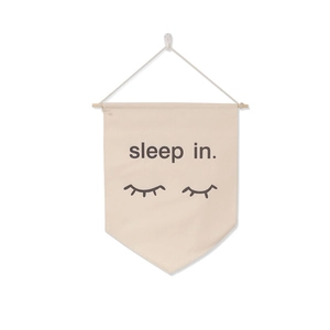 Detail of beige canvas wall banner with sleep in text and closed eyes pattern