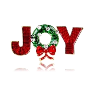 Close-up of JOY Christmas brooch with red enamel and green rhinestone wreath on gold base