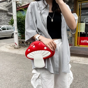 Outdoor model wearing a red and white polka dot mushroom PU crossbody bag with silver chain