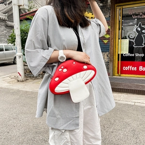 Street style shot of a woman wearing a red mushroom-shaped PU crossbody bag with white dots