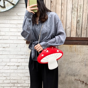Close-up of cute red mushroom crossbody bag with white dots and silver chain strap