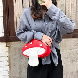 Detail of red mushroom crossbody bag with white dots and silver chain on a model