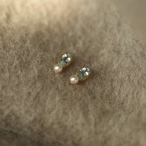 Macro shot of 14K gold-plated S925 silver stud earrings with blue topaz and white pearl