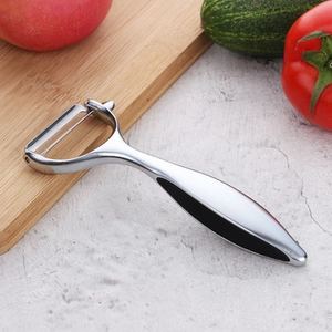 Close-up of a stainless steel vegetable peeler with a non-slip handle on a wooden board