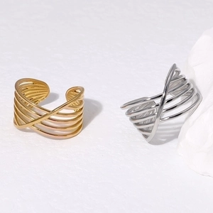 Crossed multi-layer geometric open rings in gold and silver finish on white stone