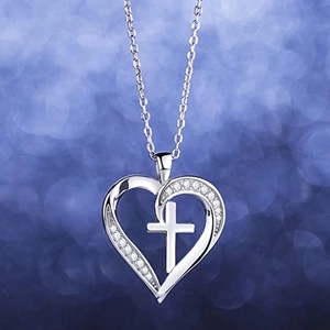 Elegant heart and cross pendant necklace with zircon accents on a blue bokeh background
