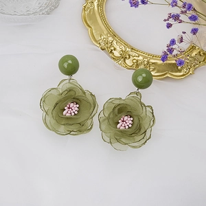 Détail d'une boucle d'oreille en maille verte avec perle rose et résine stud
