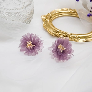 Vue détaillée de boucles d'oreilles fleurs en mousseline violette avec étamines jaunes