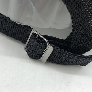 Detailed macro view of the adjustable metal buckle on a black mesh baseball cap