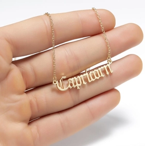 Detail of gold Capricorn pendant necklace with gothic font on a delicate cable chain