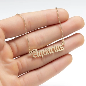 Detailed close-up of a golden Aquarius zodiac pendant necklace held in hand