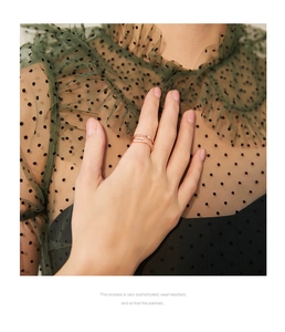 Detailed close-up of rose gold layered crisscross ring with pavé zircons on finger